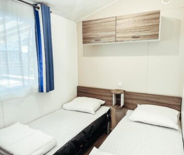 Chambre avec deux lits simples et fenêtre dans le chalet 3 bedroom Chalets Camping Leï Suves JoyCasa