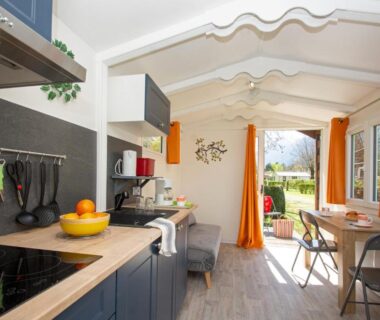 Intérieur kitchenette et coin repas avec baie vitrée sur extérieur du camping A La Rencontre Du Soleil