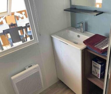 Salle d'eau avec lavabo et fenêtre donnant sur terrasse du mobil home A la brise du Ferret Camping les Embruns