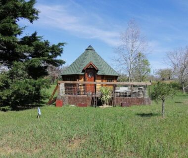 Prairie et petite cabane en bois sur pilotis au camping A l'abri des cyprès