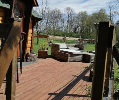 Terrasse en bois avec salon extérieur et jardin du camping A l'abri des cyprès