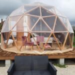 Terrasse avec dôme géodésique transparent et mobilier extérieur au camping A l'aube des sens