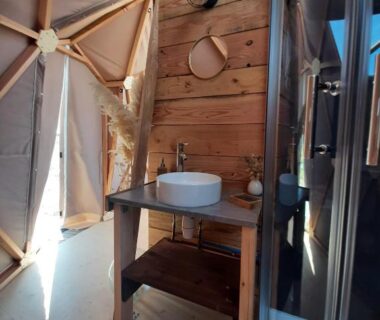 Salle d'eau dans un dôme en bois avec lavabo et douche dans l'hébergement A l'aube des sens