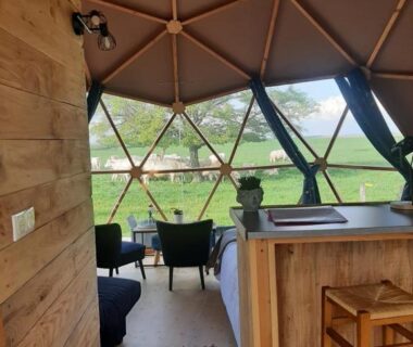 Intérieur du dôme avec kitchenette coin salon et vue sur prairie dans A l'aube des sens