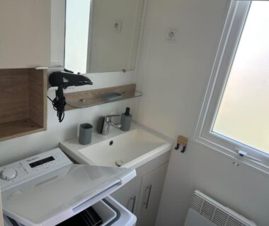Salle de bains avec lavabo miroir sèche-cheveux et lave-linge dans l'AA-Luminosa