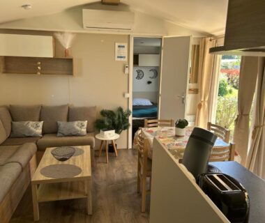 Salon avec canapé et coin repas dans le mobil-home AA-Luminosa