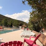 Bord de piscine avec transats et fauteuils colorés à l'Aloha Camping Club