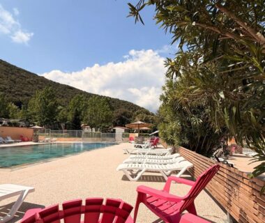 Bord de piscine avec transats et fauteuils colorés à l'Aloha Camping Club