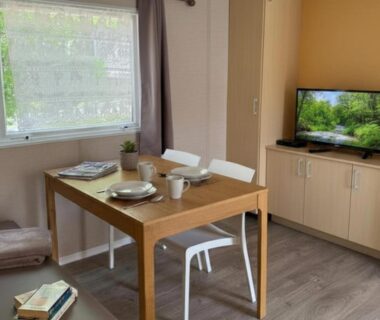 Intérieur avec table à manger et télévision dans le mobil-home Aloha Camping Club