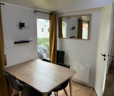 Intérieur du mobil-home avec table à manger et baie vitrée dans l'Amira 6-8 personnes