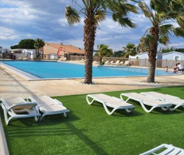 Bord de piscine avec transats et palmiers au camping Anthony MH 140