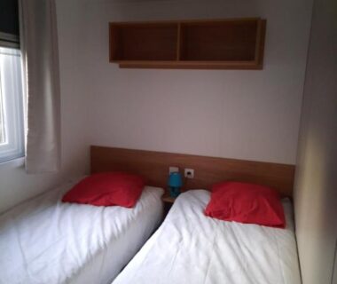 Chambre avec deux lits simples et coussins rouges dans le camping Aquapark -DESS
