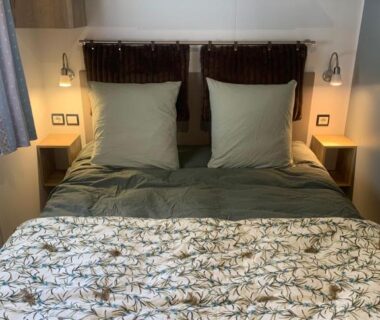 Chambre avec lit double lampes et étagères dans le mobil home Au Petit Bonheur
