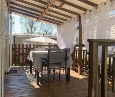 Terrasse couverte avec table et chaises au camping Au Petit Bonheur