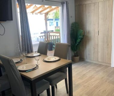 Séjour avec table à manger et baie vitrée dans le mobil home Au Petit Bonheur