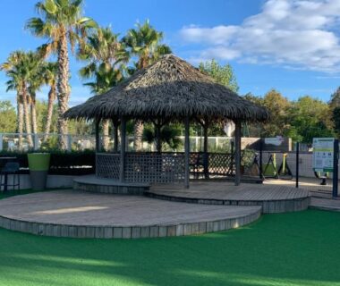 Kiosque en toit de paille et palmiers au camping Au Petit Bonheur