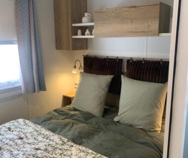Chambre avec lit double coussins et étagères dans l'hébergement Au Petit Bonheur