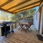 Terrasse couverte avec table et barbecue du camping Au coeur de la pinède