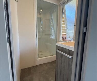 Salle de bain avec cabine de douche et lavabo dans l'hébergement Au coeur de la pinède