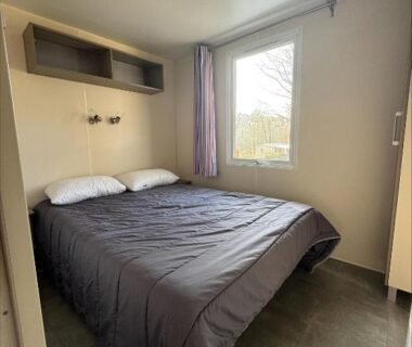 Chambre avec lit double et fenêtre au camping Au coeur de la pinède