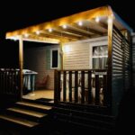 Terrasse en bois éclairée la nuit du mobil-home Au cœur des Pins