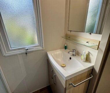 Salle de bains avec lavabo et miroir dans l'hébergement Au cœur des Pins