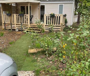 Mobil-home avec terrasse en bois au milieu des arbres au camping Au petit paradis