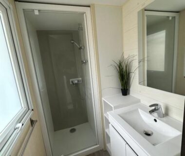 Salle de bains avec douche vitrée et lavabo au camping Au p'tit bonheur