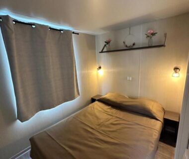 Chambre avec lit double et lampes murales au mobil-home Au p’tit bonheur