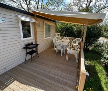 Terrasse en bois avec table et chaises et barbecue du mobil-home Au p’tit bonheur