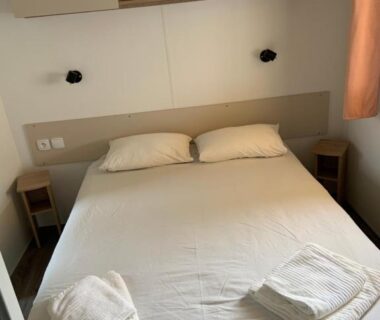 Chambre avec lit double et serviettes dans le bungalow Au viviers camping Siblu sublime