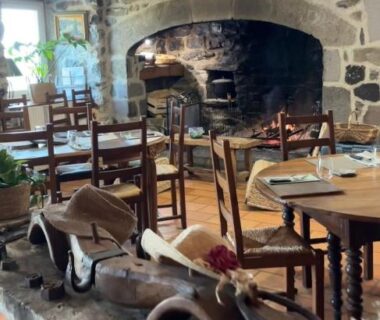 Salle à manger aux murs en pierre et cheminée à l'Auberge et Camping Sabatoux