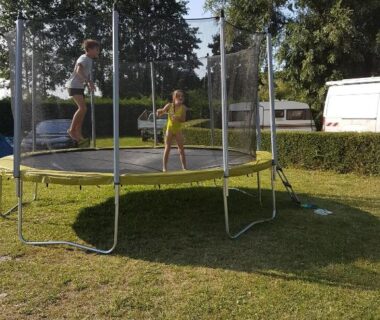 Aire de jeux avec trampoline et enfants au camping Aux Cygnes D'Opale