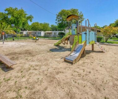 Aire de jeux avec toboggan et bancs dans le camping Awesome Stacaravan In Saint-Georges-De-Didon