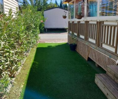 Allée avec pelouse synthétique et terrasse de mobil-home du camping Azur072