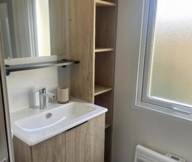Salle d'eau avec lavabo miroir et fenêtre dans le logement BT Le Soleia
