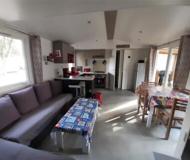 Intérieur salon avec canapé table et coin cuisine du Bungalow Luxe Mazet Royal Carabasse