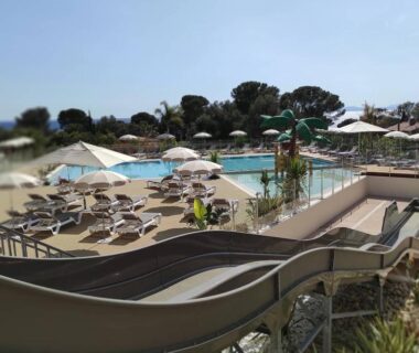 Espace piscine avec toboggan et transats au camping Baia 1