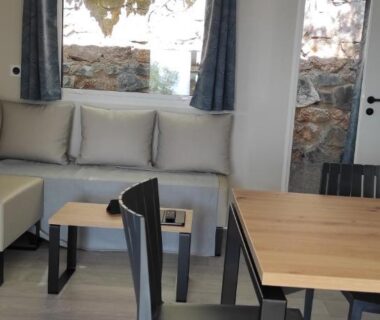 Salon intérieur avec canapé et coin repas dans le mobil-home Baia 1