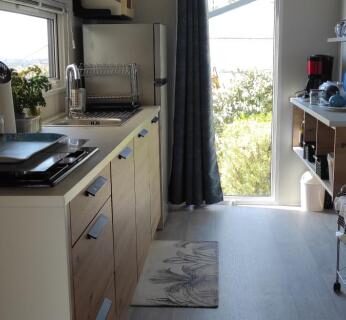 Cuisine aménagée avec porte ouverte sur l'extérieur du mobil-home Baia 1