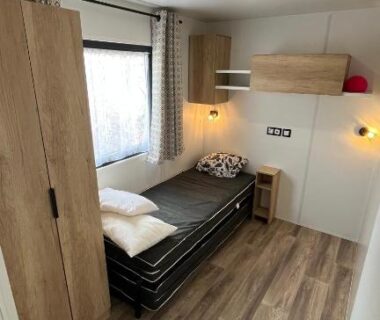 Chambre avec lit simple penderie et fenêtre au camping Bayaïna