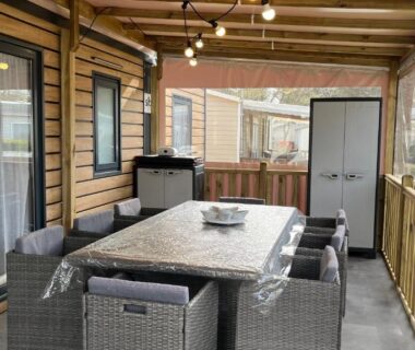 Terrasse couverte avec table à manger et chaises en rotin du camping Bayaïna