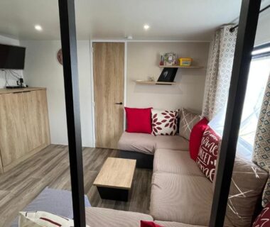 Salon avec canapé d'angle table basse et télévision dans le camping Bayaïna