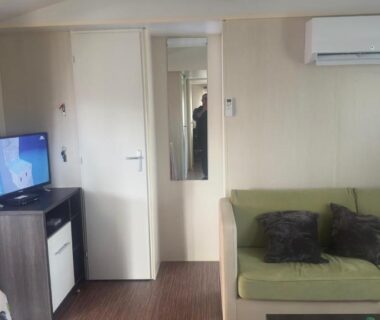 Salon avec canapé, climatisation et télévision dans le Beau Mobilhome 6 à 8p tout confort