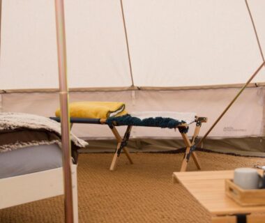 Intérieur de tente avec lit de camp et table au Belair le Camping