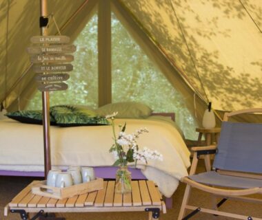 Intérieur de tente avec lit table et fauteuil au Belair le Camping