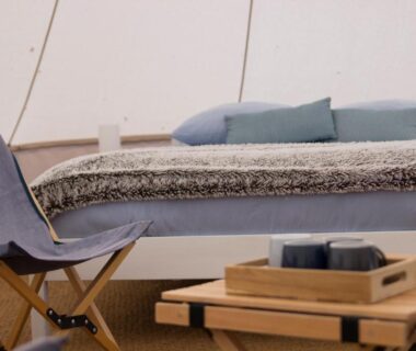 Intérieur de tente aménagée avec lit et table basse au Belair le Camping