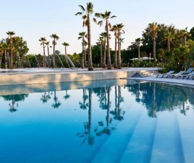 Bord de piscine avec palmiers et chaises longues au camping Best Holiday Port Grimaud