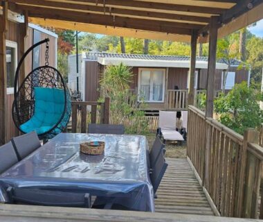 Terrasse couverte avec table et fauteuil suspendu au camping Bienvenue au Cap Ferret