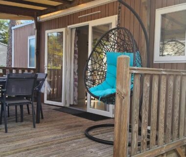 Terrasse en bois avec fauteuil suspendu et table à manger du camping Bienvenue au Cap Ferret
